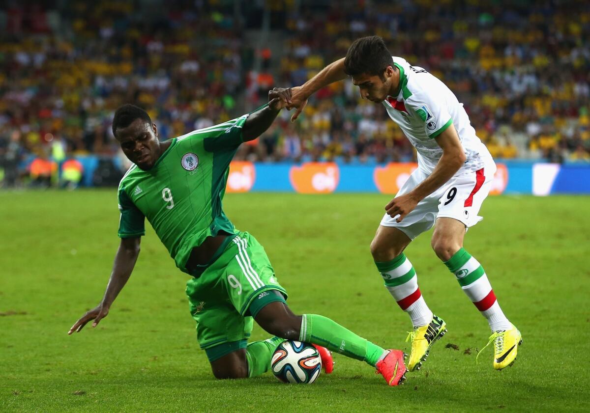 Emmanuel Emenike of Nigeria, left, and Alireza Jahan Bakhsh of Iran battle for the ball during a Group F match at the World Cup.