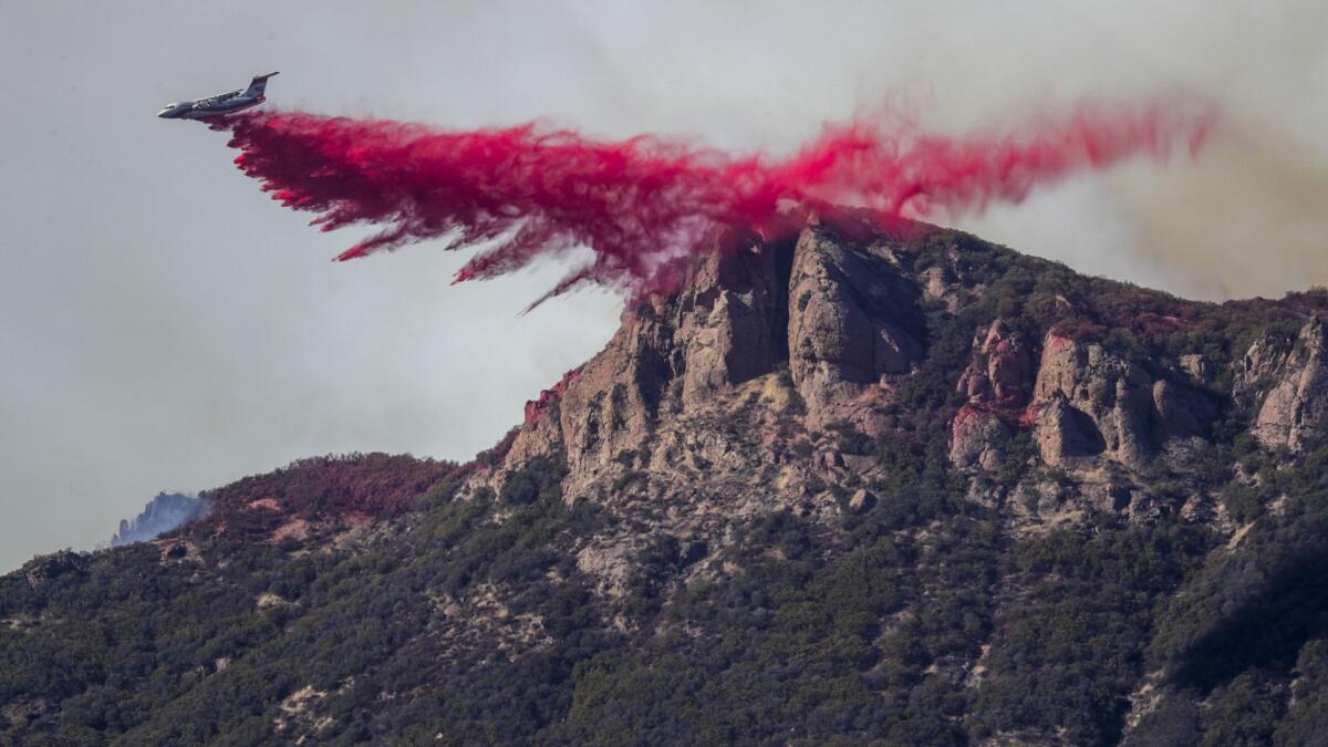 A plane drops retardant on the Woolsey fire burning above Lake Sherwood.