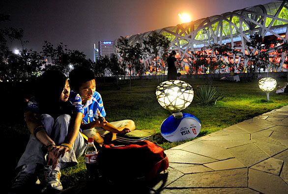 Volunteers relax outside the Bird's Nest stadium during the closing ceremony.