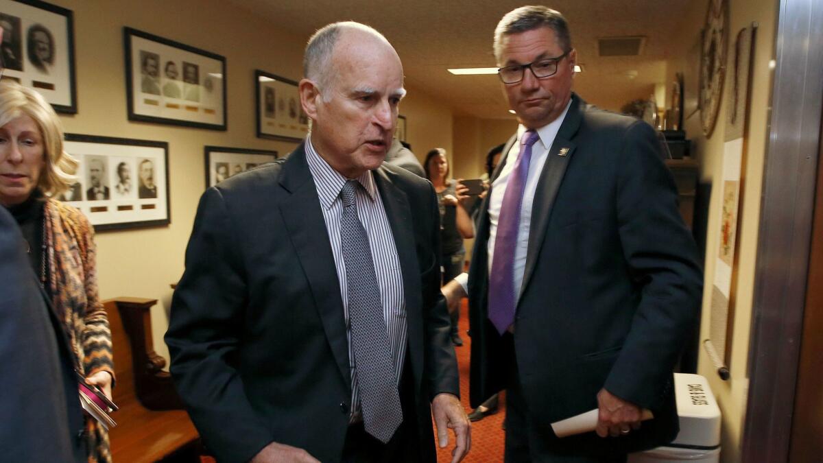 Gov. Jerry Brown walks into a meeting of the Senate Democratic Caucus to urge members to approve a transportation plan on April 6.