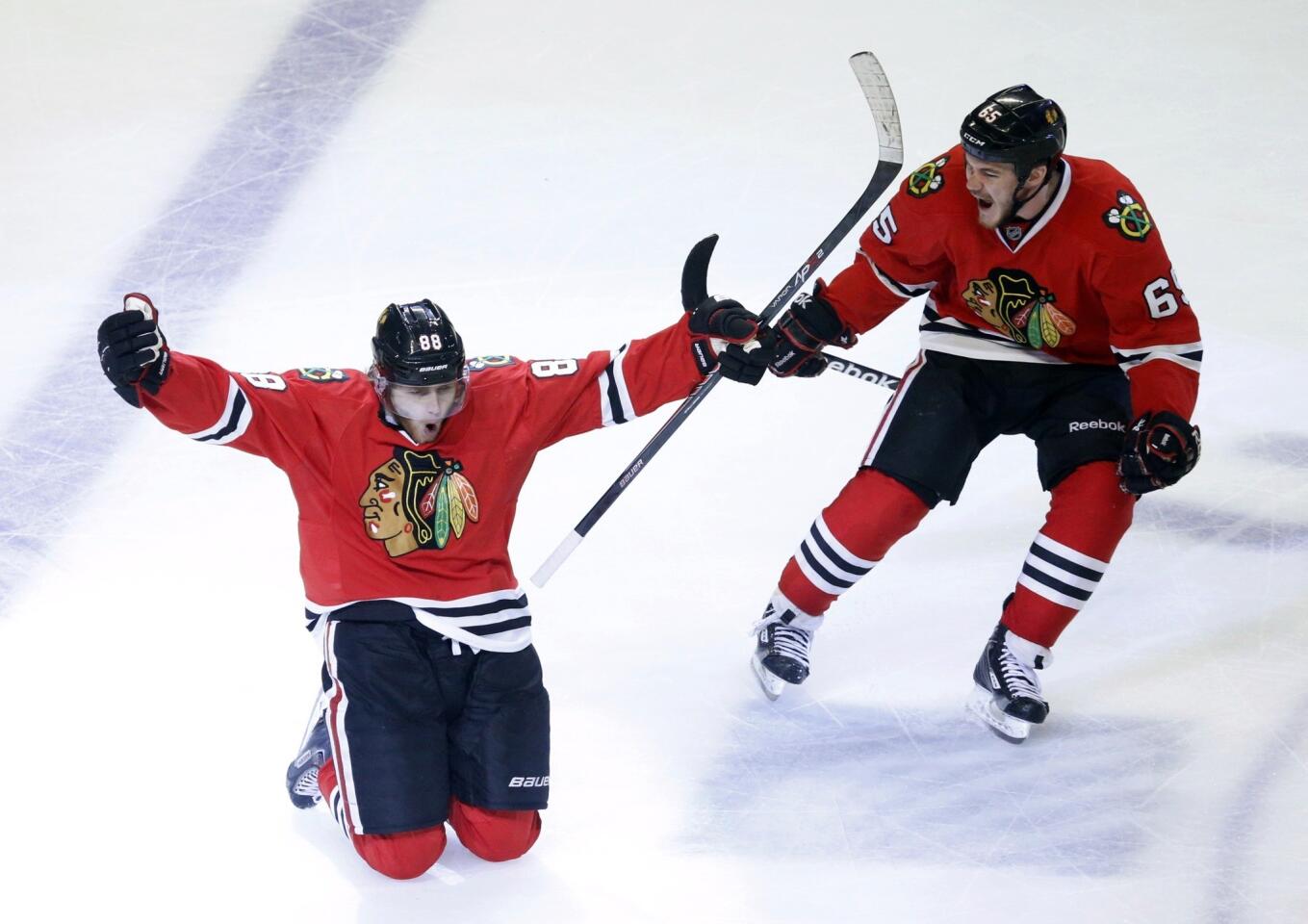 Blackhawks right wing Patrick Kane celebrates with a slide on his knees next to teammate Andrew Shaw after scoring the game-winning goal against the Kings in the second overtime period of Game 5 on Saturday night at United Center in Chicago.