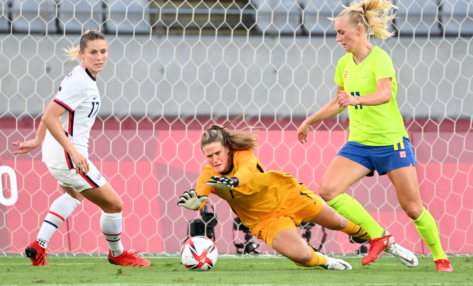 USA goalie Alyssa Naeher makes a save in front of teammate Abby Dahlkemper and Sweden's Stina Blackstenius