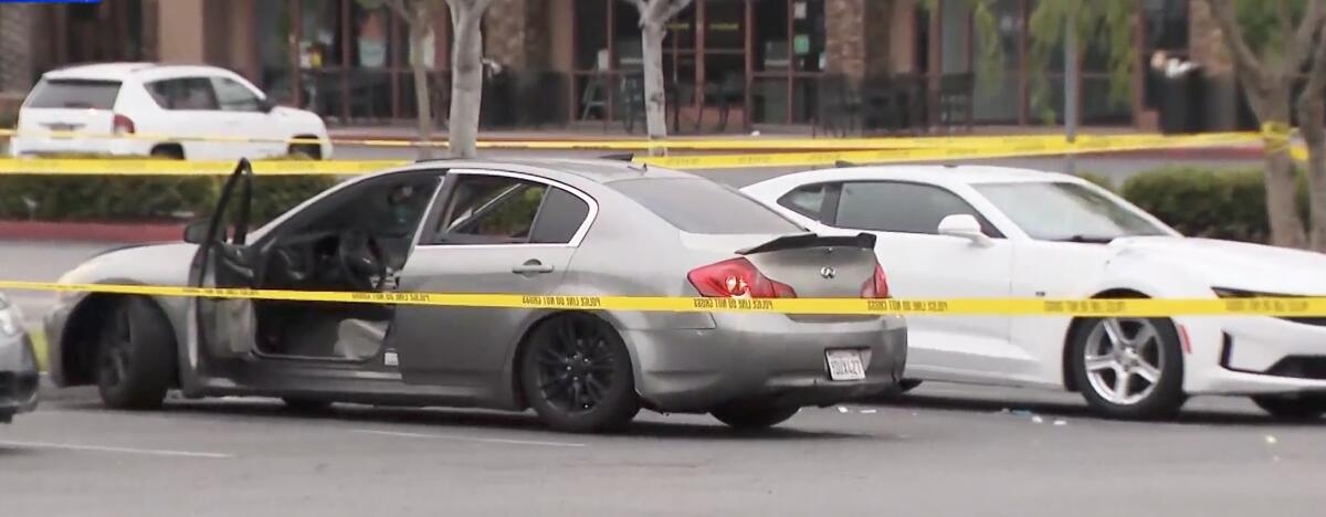 Police tape surrounds two sedans, one with its driver's door open, in a Walmart parking lot in La Habra 