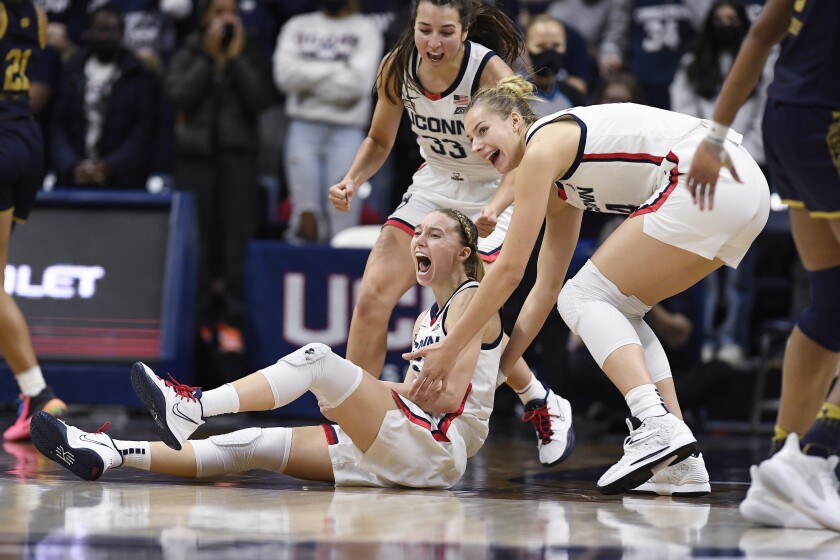 Connecticut's Paige Bueckers, bottom left, reacts with teammates Caroline Ducharme, back, and Dorka Juhász, right, in the second half of an NCAA college basketball game against Notre Dame, Sunday, Dec. 5, 2021, in Storrs, Conn. (AP Photo/Jessica Hill)