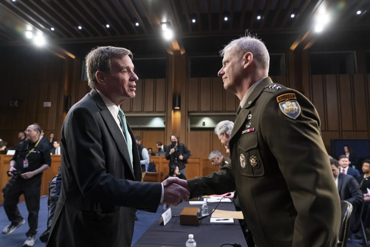 Senate Intelligence Committee Chairman Mark Warner, D-Va., left, greets Defense Intelligence Agency Director Lt. Gen. Scott Berrier, right, at the start of a hearing on worldwide threats as Russia continues to attack Ukraine, at the Capitol in Washington, Thursday, March 10, 2022. (AP Photo/J. Scott Applewhite)