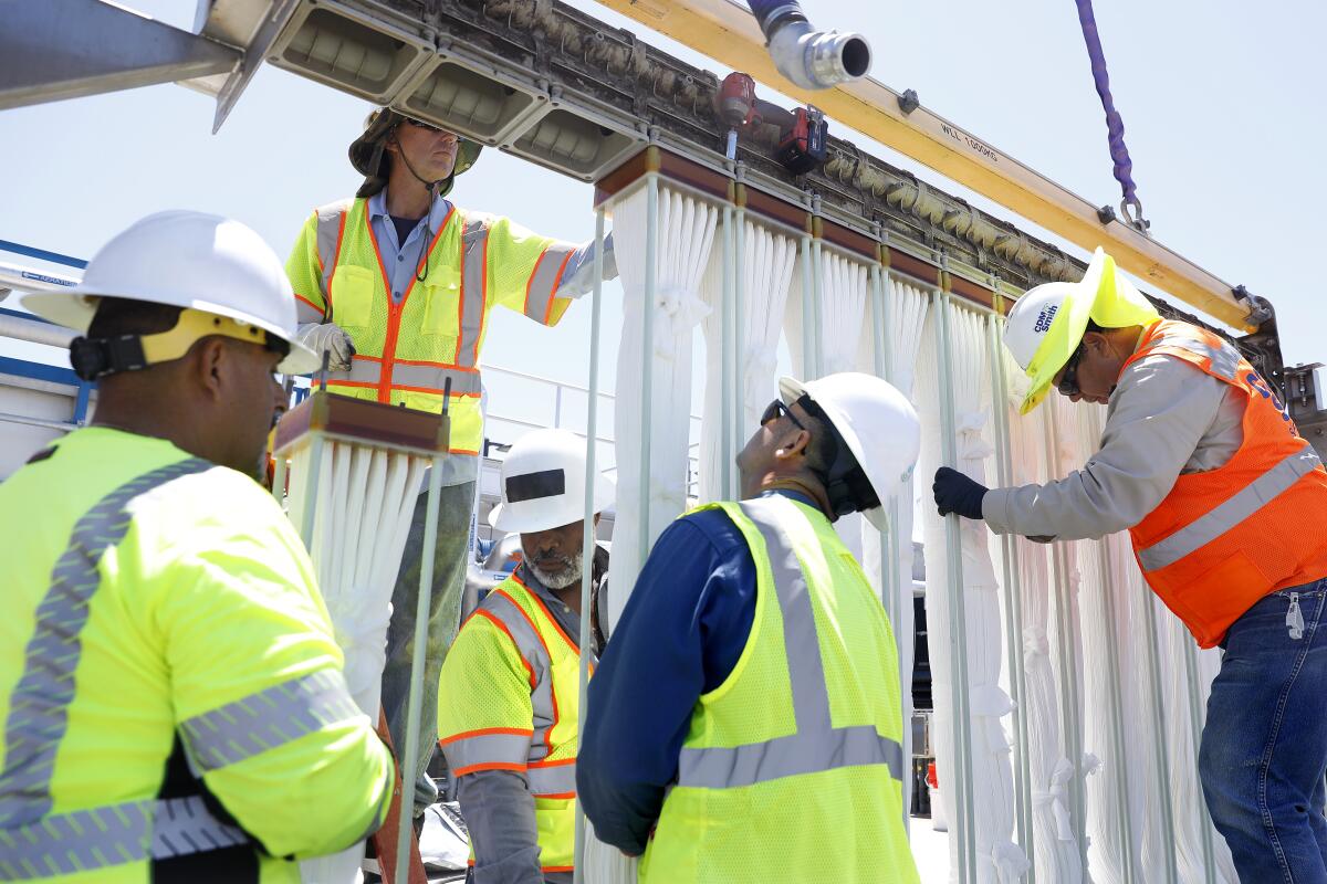 Workers install membrane bioreactors at Metropolitan Water District's pilot water recycling facility in Carson.