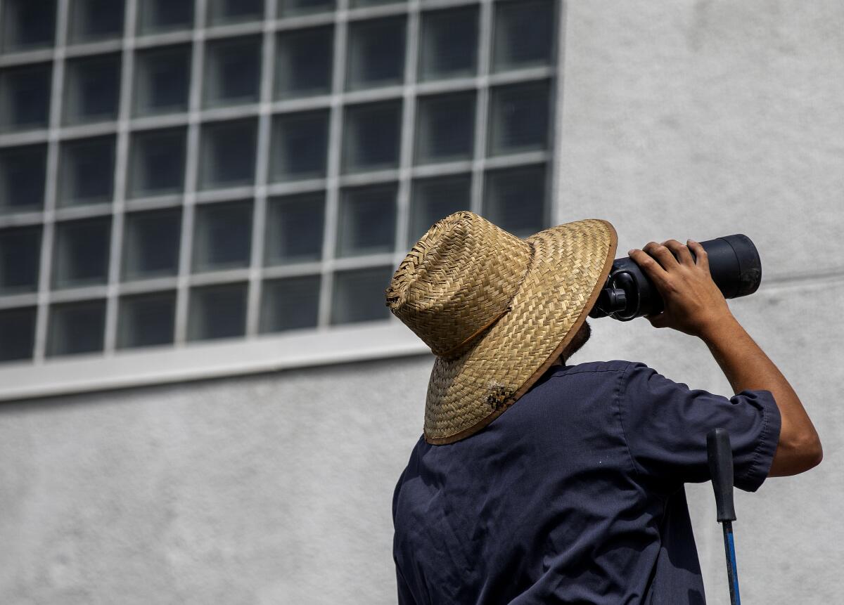 A man in a straw hat drinks from a water bottle.