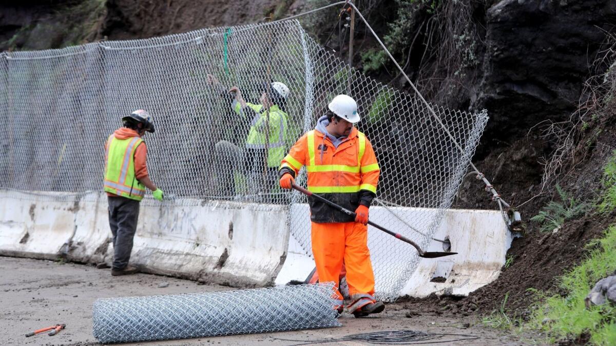 Workers from Access Limited Construction put up barricades in February after a mudslide closed Topanga Canyon Boulevard in Topanga.