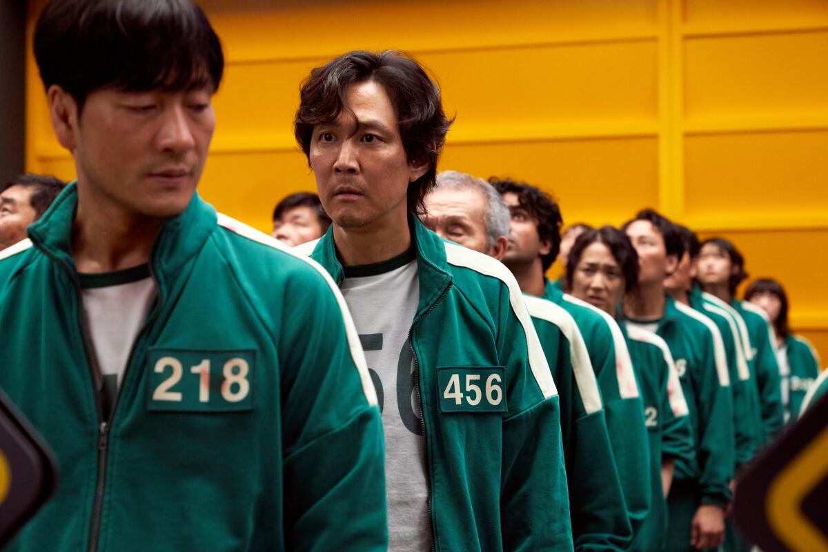 Contestants in green track suits stand in lines.