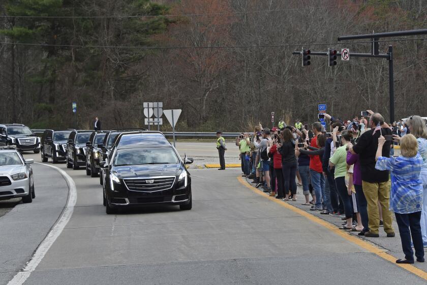 People watch as the hearse carrying the body of Billy Graham leaves Asheville, N.C., Saturday, Feb. 24, 2018. Graham's body was brought to his hometown of Charlotte on Saturday, Feb. 24, as part of a procession expected to draw crowds of well-wishers. (AP Photo/Kathy Kmonicek, Pool)