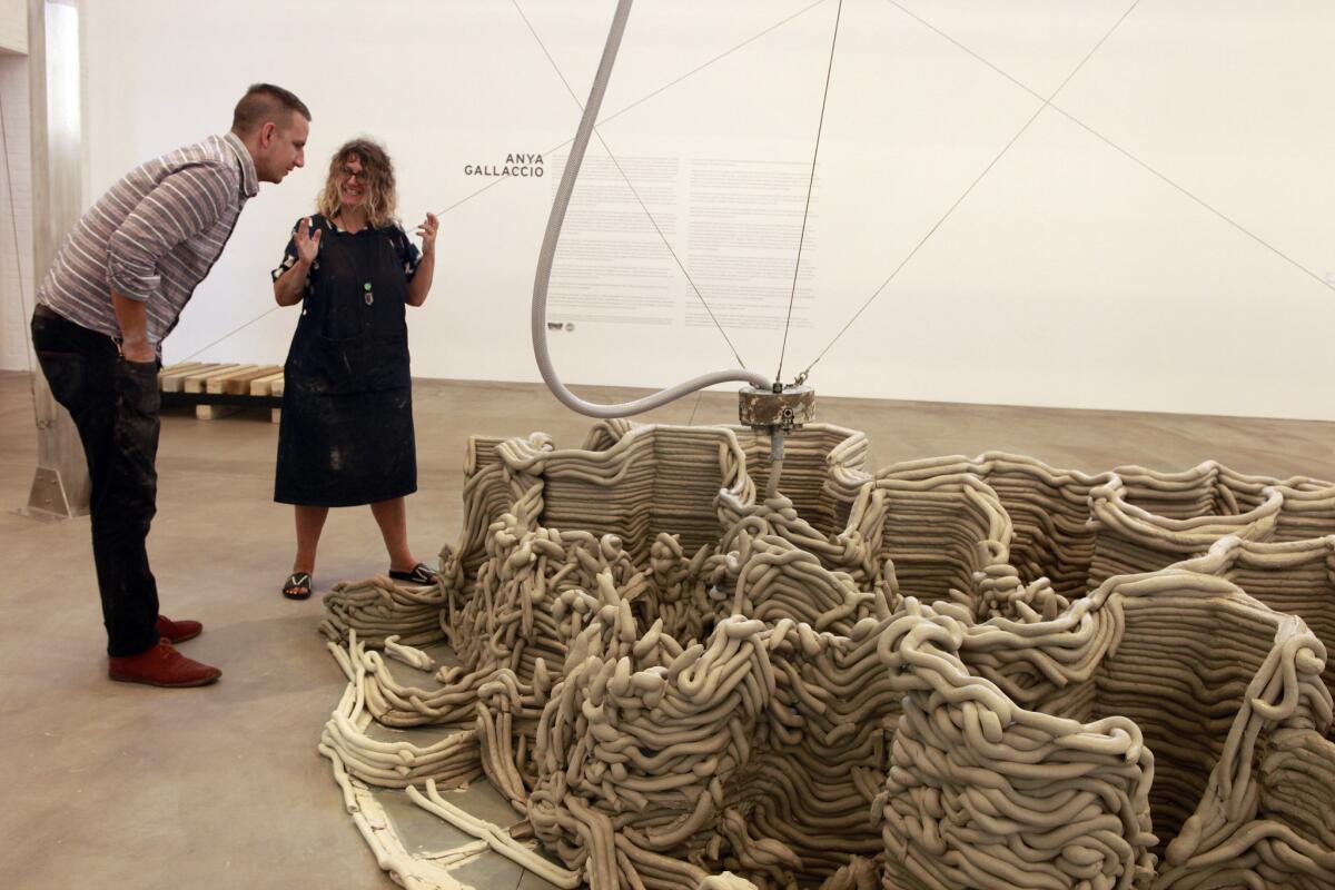 Anya Gallaccio, local artist and professor from the University of California, San Diego, and Josh Miller, an assistant, discuss the clay formation from the Devil Tower creation July 23, 2015, at the Museum of Contemporary Art.