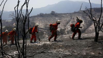 A fire crew made up of prison inmates climbs through a burned area in Hidden Valley looking for hot spots.