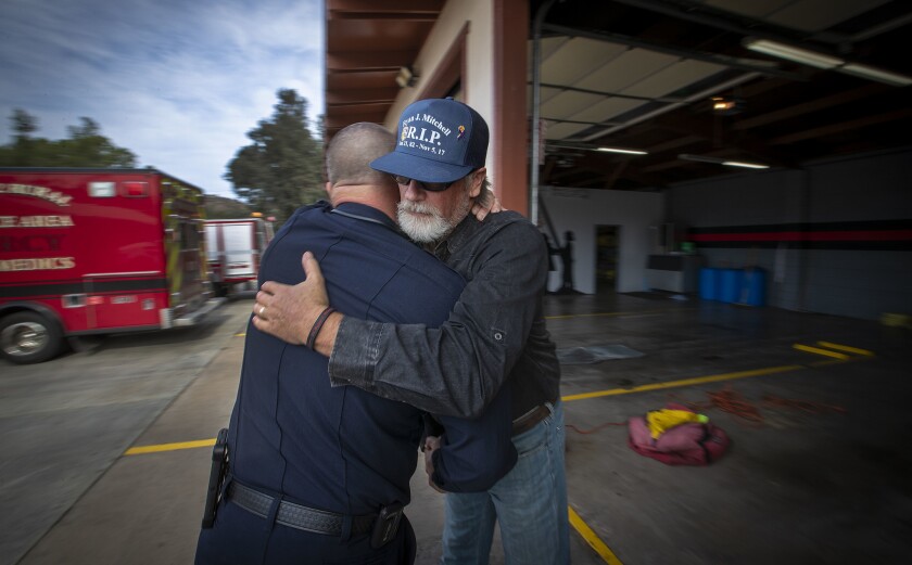 Cal Fire Battalion Chief Ernie Marugg, left, hugs Will Mitchell, whose son Ryan Mitchell killed himself in November 2017 after working a shift at Cal Fire's San Diego unit.