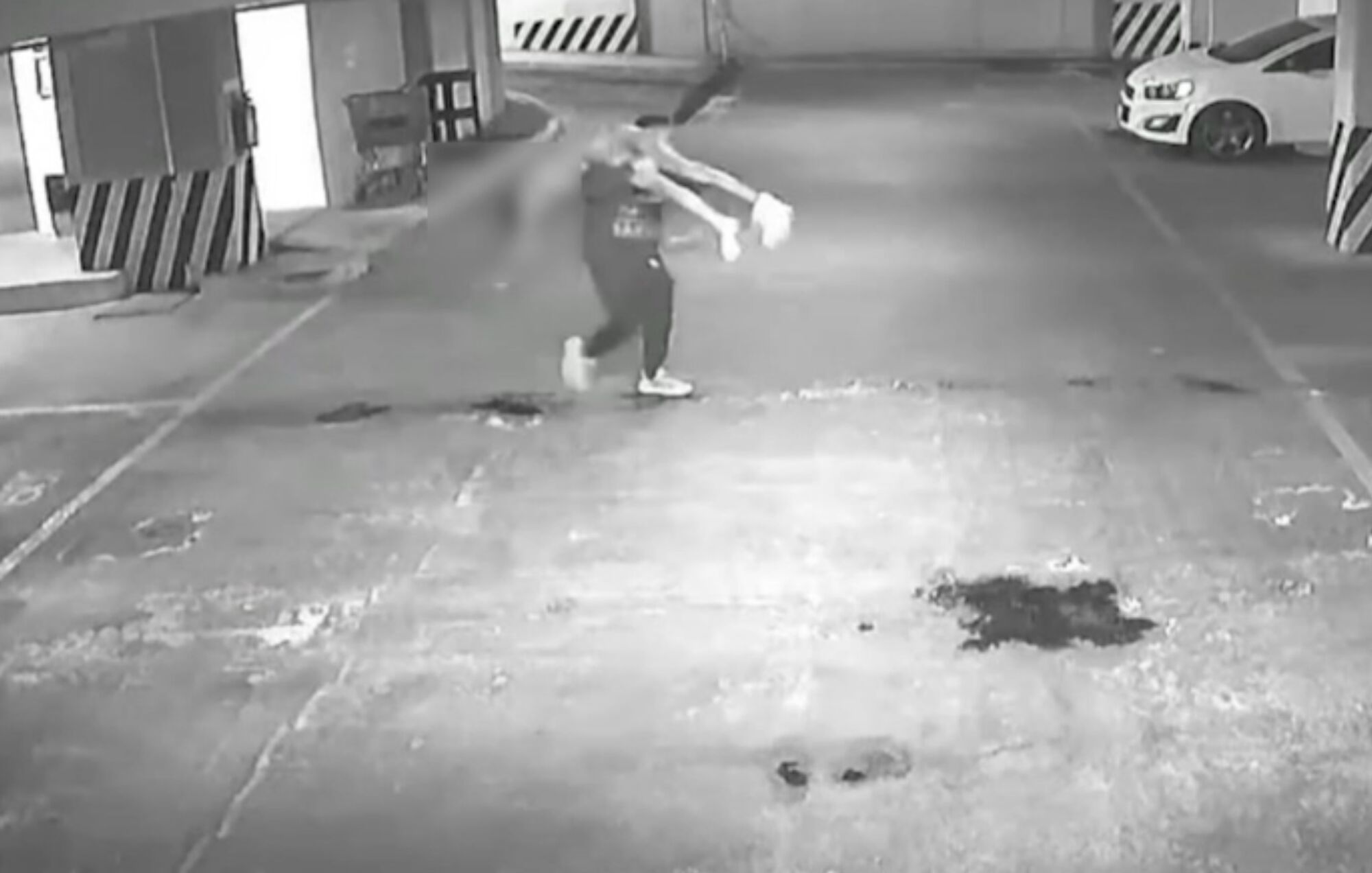 A still from a security camera shows a man carrying a woman's body.