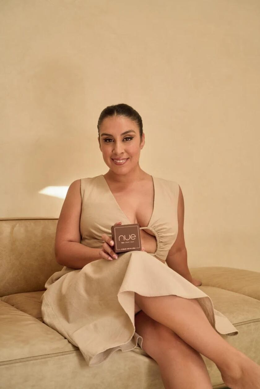 Stephanie Montes sits on a couch holding a carved block.