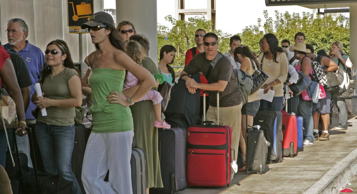 Travelers line up outside the Southwest Airlines terminal at LAX during the busy summer travel season. A $500-million remodel of the terminal is set to begin.