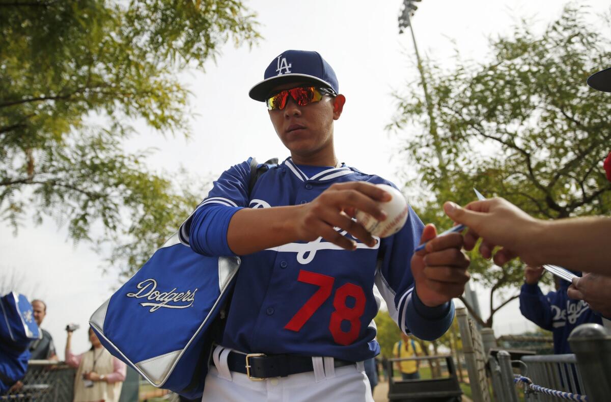 Los Angeles Dodgers' Julio Urias signs a ball for a fan during the team's first pitchers and catchers workout Friday, Feb. 20, 2015, in Phoenix. (AP Photo/John Locher)
