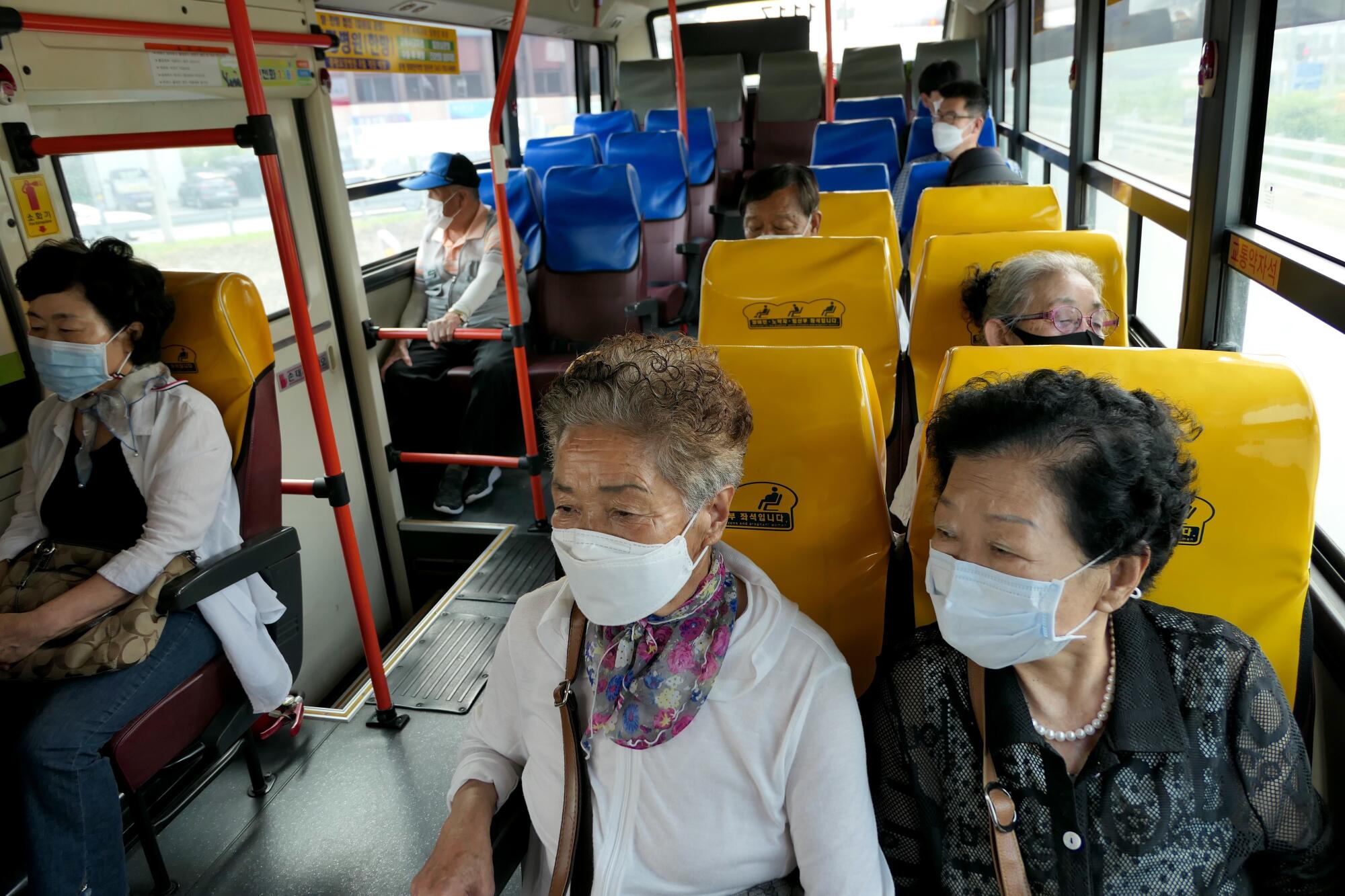 Older people ride a bus with some empty seats