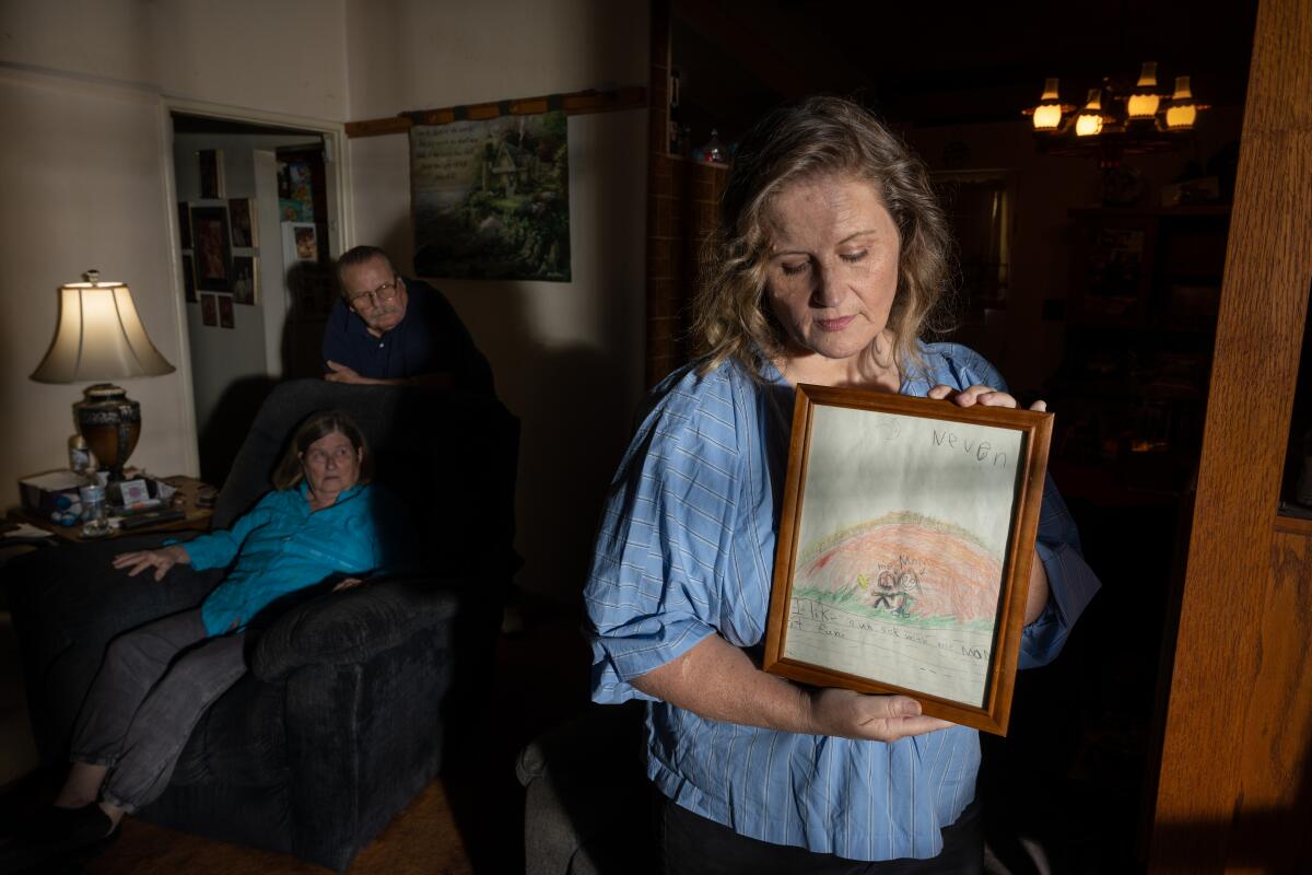 A woman holds a framed child's drawing