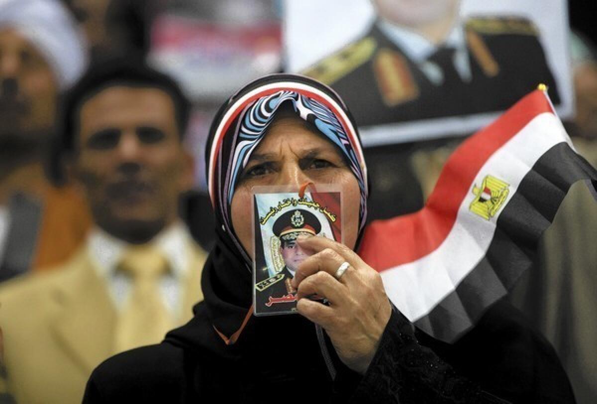A woman at a rally in Cairo kisses a picture of Gen. Abdel Fattah Sisi, Egypt's de facto leader. Sisi will probably win the presidential election if he runs, but he might wield more authority if he retains his military post instead.