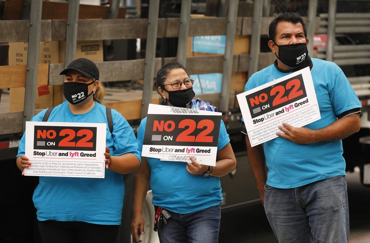 Three demonstrators holding "No on 22" protest signs. 