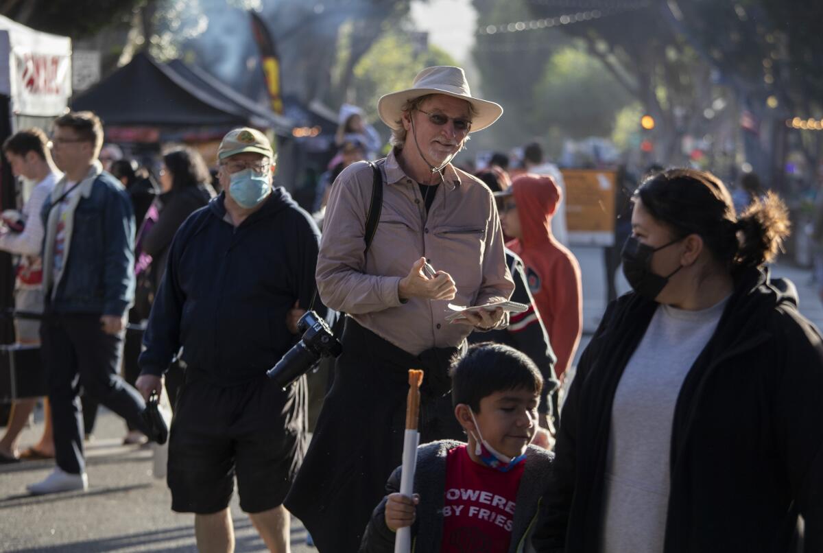 Los Angeles Times reporter Christopher Reynolds stands in a crowd of people taking notes.