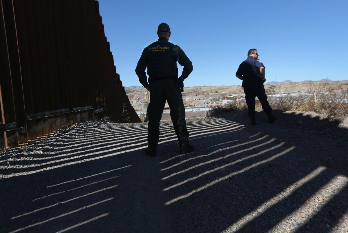 Border Patrol agents stand at the U.S.-Mexico border fence in Nogales, Arizona.