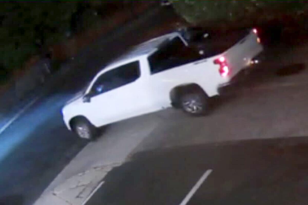 A white pickup truck driving in an alleyway at night