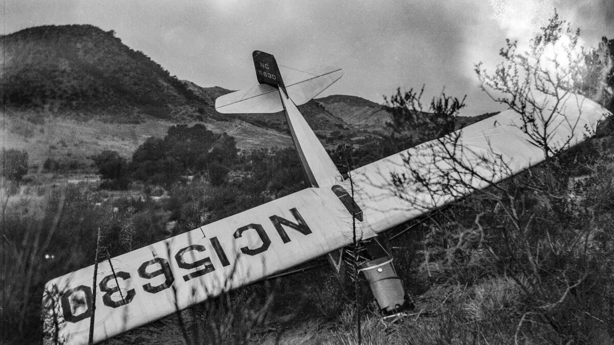 a small airplane with damage sticks out of a ditch
