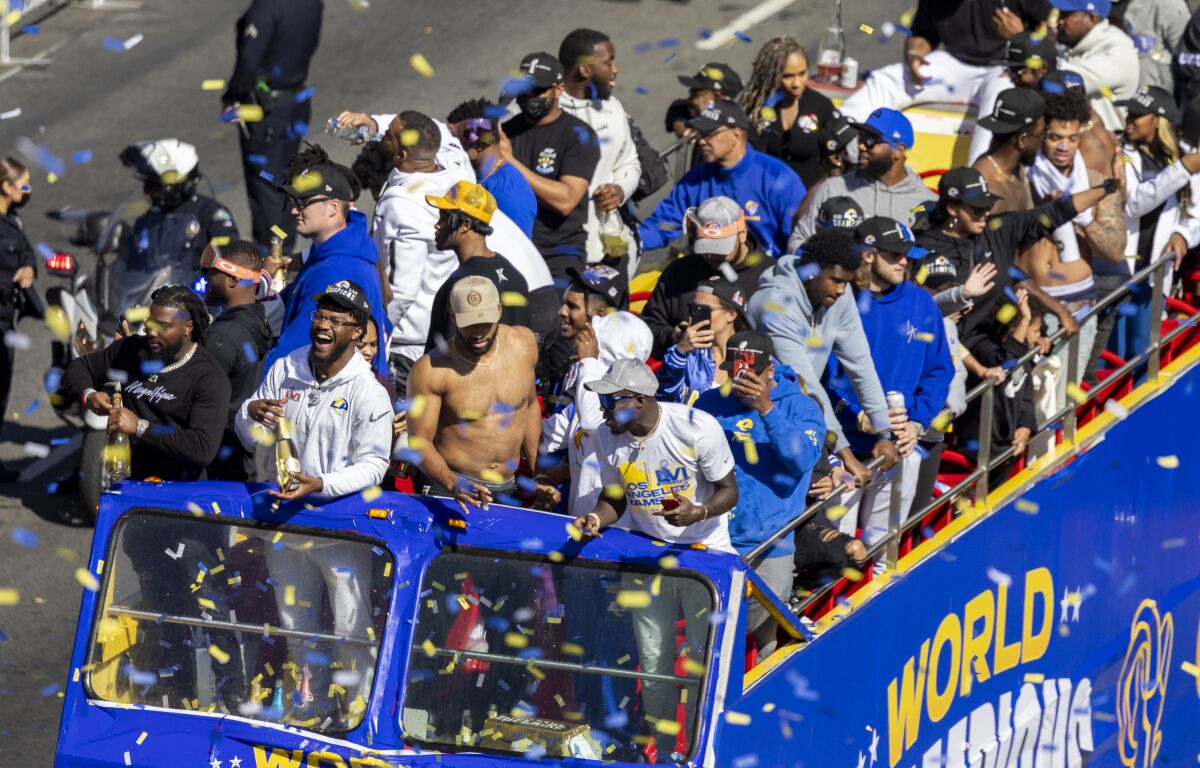 The champion Rams ride double-decker buses down Figueroa Street as fans cheer during a victory parade.