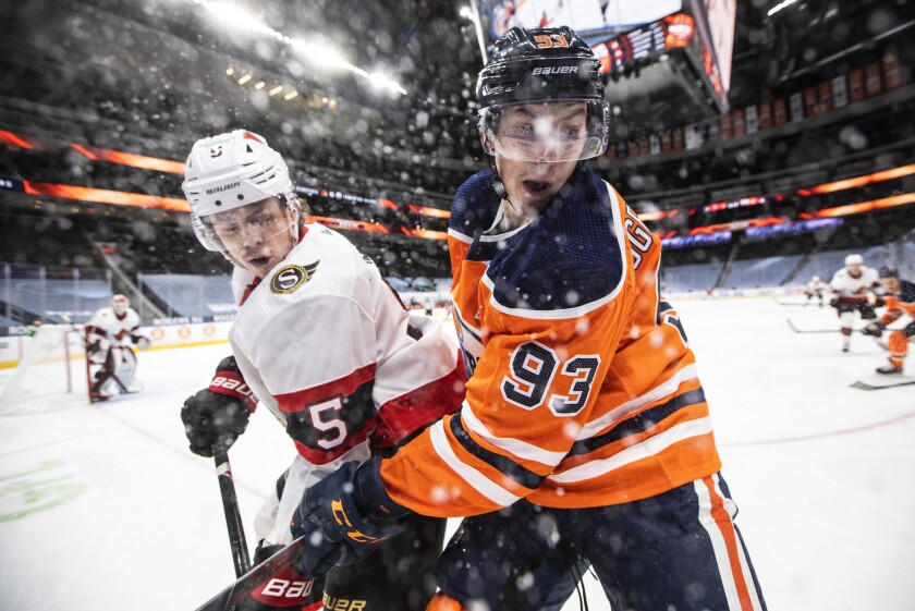 Edmonton Oilers' Ryan Nugent-Hopkins (93) and Ottawa Senators' Mike Reilly (5) vie for the puck during the second period of an NHL hockey game Tuesday, Feb. 2, 2021, in Edmonton, Alberta. (Jason Franson/The Canadian Press via AP)