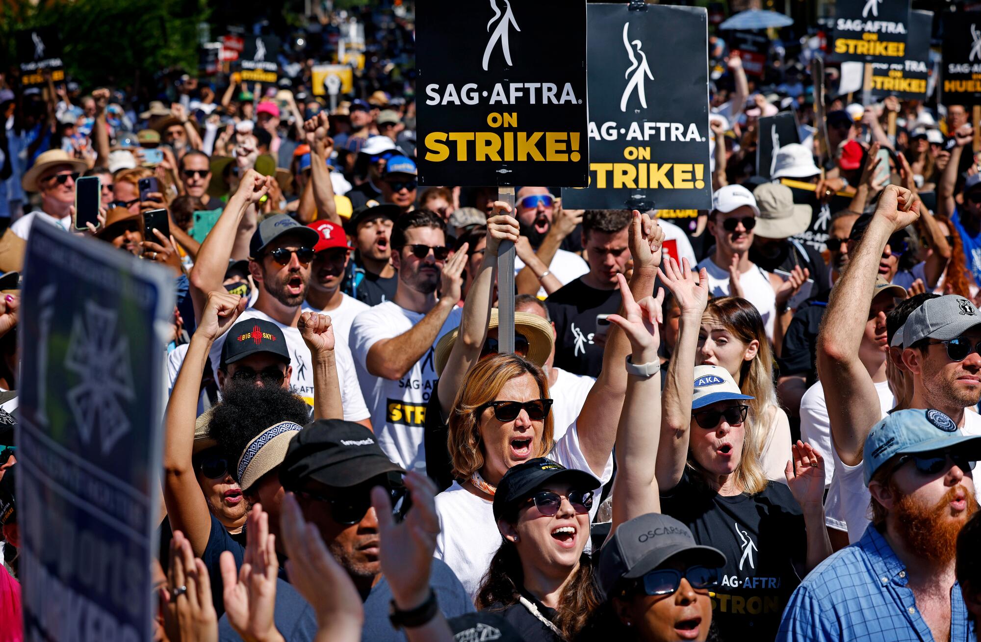 People standing in a crowd holding SAG-AFTRA picket signs.