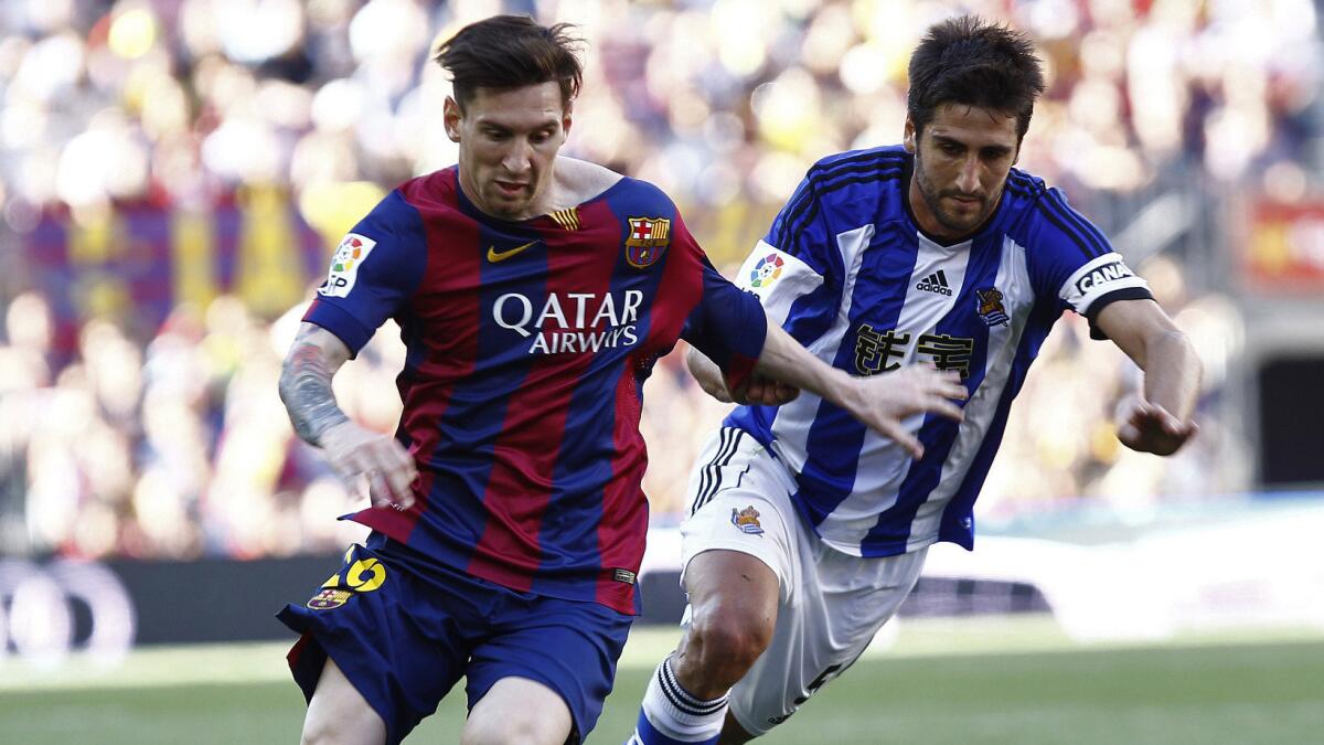 Barcelona's Lionel Messi, left, controls the ball ahead of Real Sociedad's Markel Bergara during a match on Saturday. Spanish soccer's players' union is threatening to strike over a proposed law that would change the way TV revenues will be distributed.