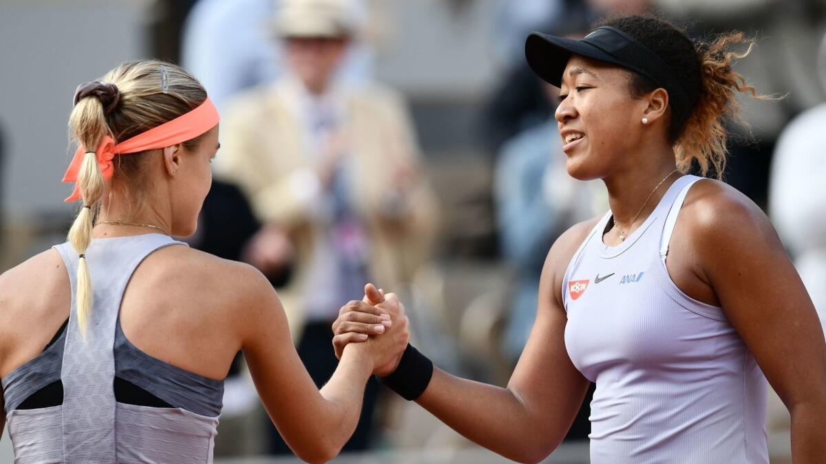 Naomi Osaka, right, and Slovakia's Anna Karolina Schmiedlova shake hands at the end of their women's singles first round match on day three of the French Open on Tuesday in Paris.