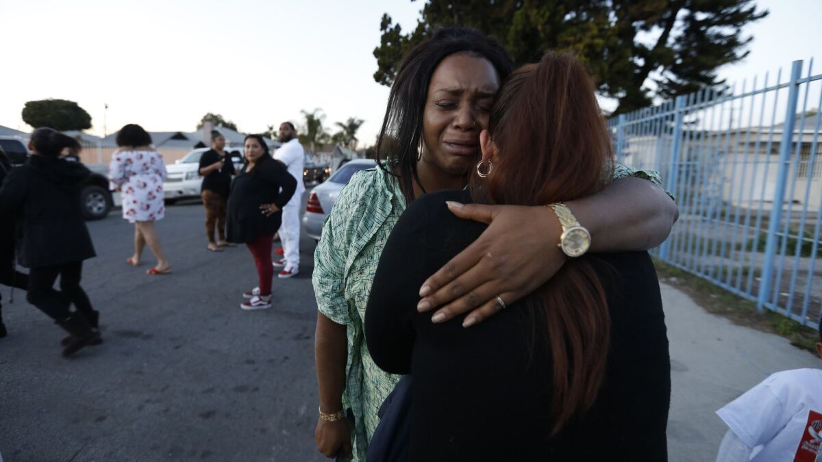 Amira Webster, left, hugs a woman after Webster's brother was killed and two others were wounded Friday in a shooting outside a church in Compton.
