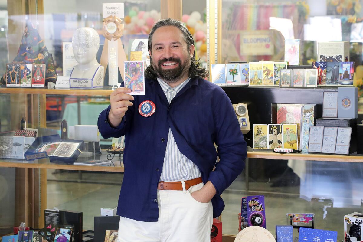 Albert Roman holds up the world tarot card as he stands in front of his featured exhibit at the Orange County Fair.