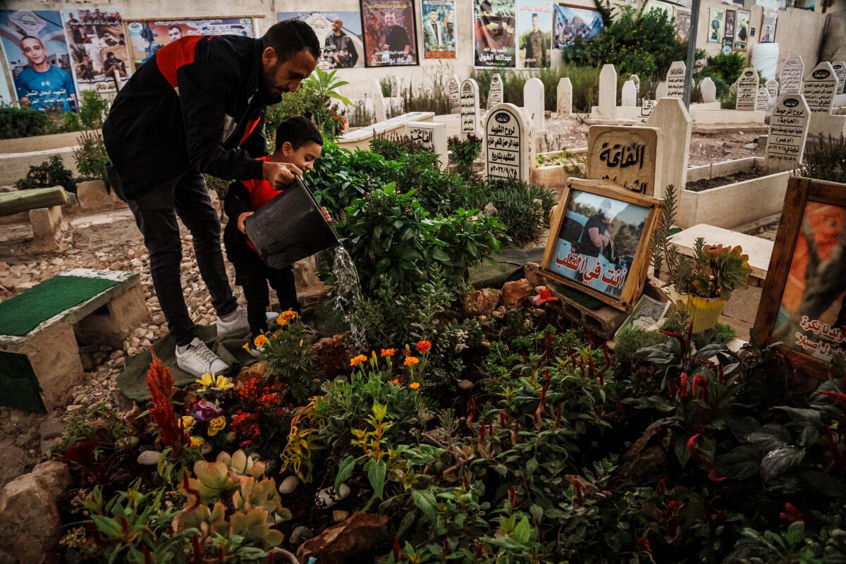 Father and son paying respects to buried Palestinian fighters