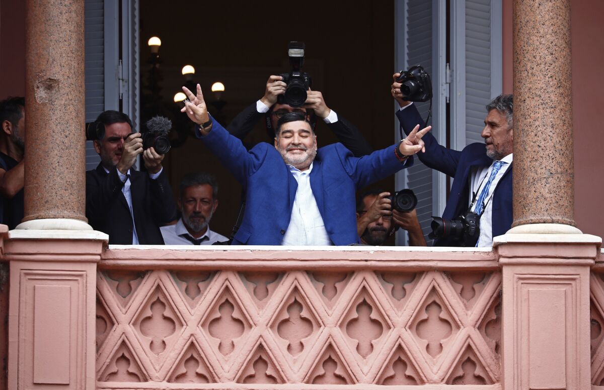 Diego Maradona flashes victory signs to fans after meeting with Argentine President Alberto Fernandez on Dec. 26, 2019.