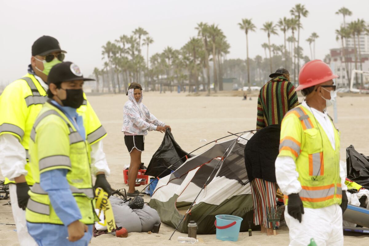 A homeless couple pack up their tent and belongings on the beach