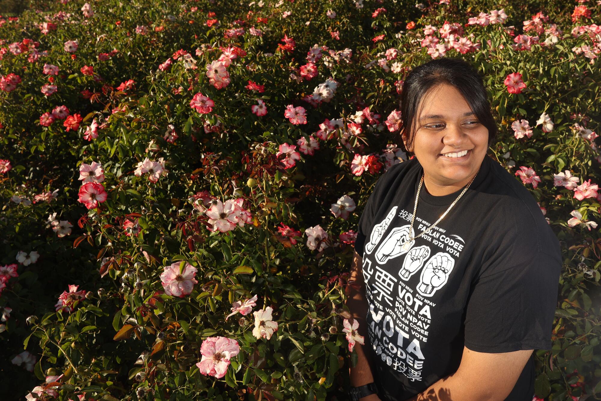 Alyssa Jaipersaud stands next to rose bushes.