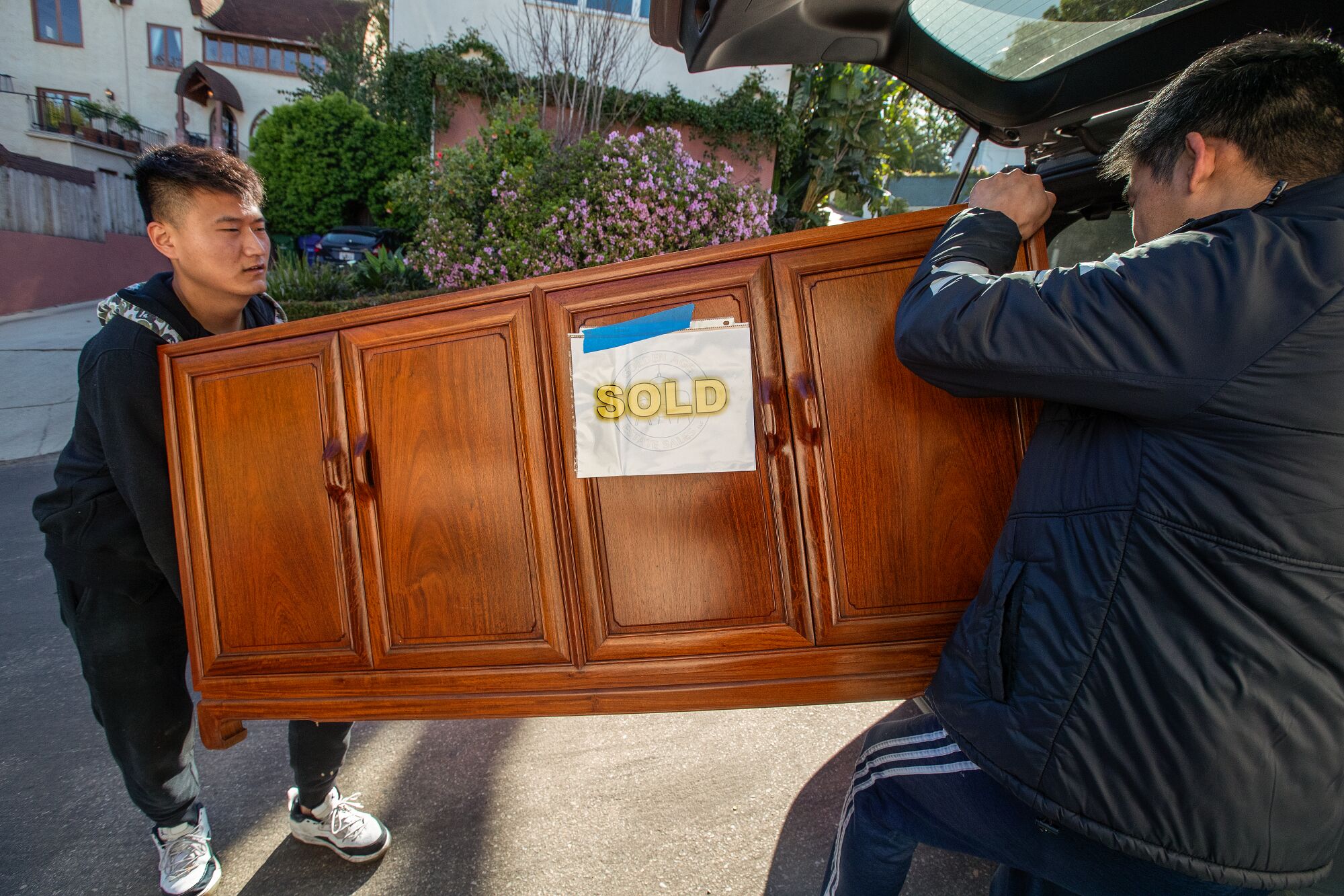 Derek Fu, left, and his brother James Qi prepare to place a hardwood oriental style cabinet into the back of their SUV.