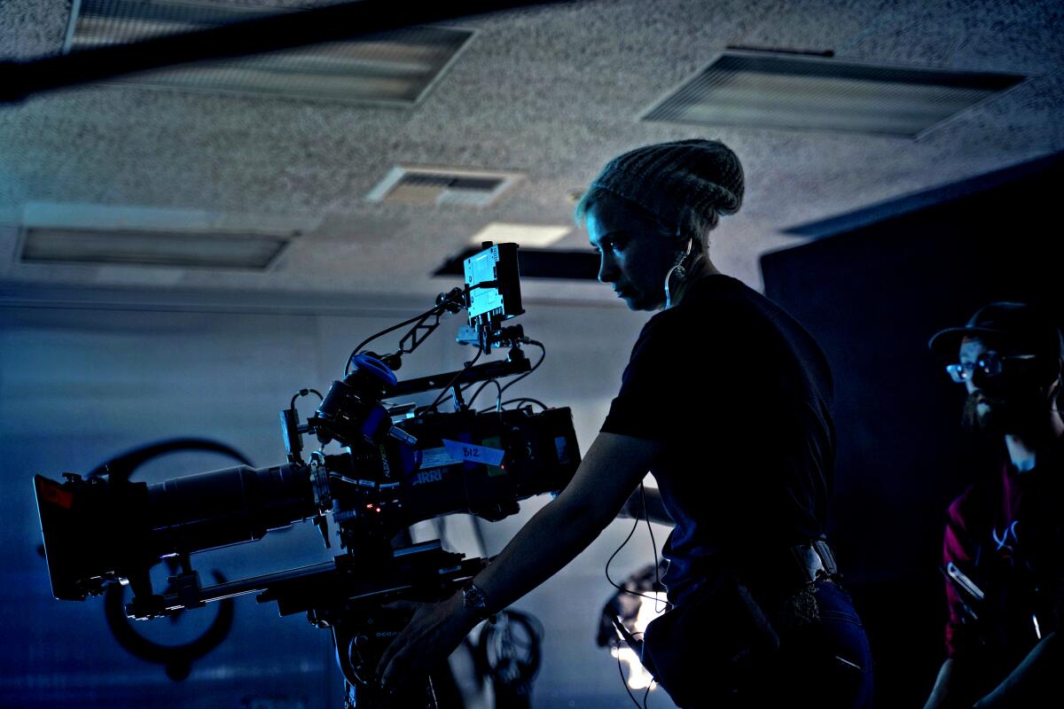  A silhouette of a woman in a knit cap behind a film camera