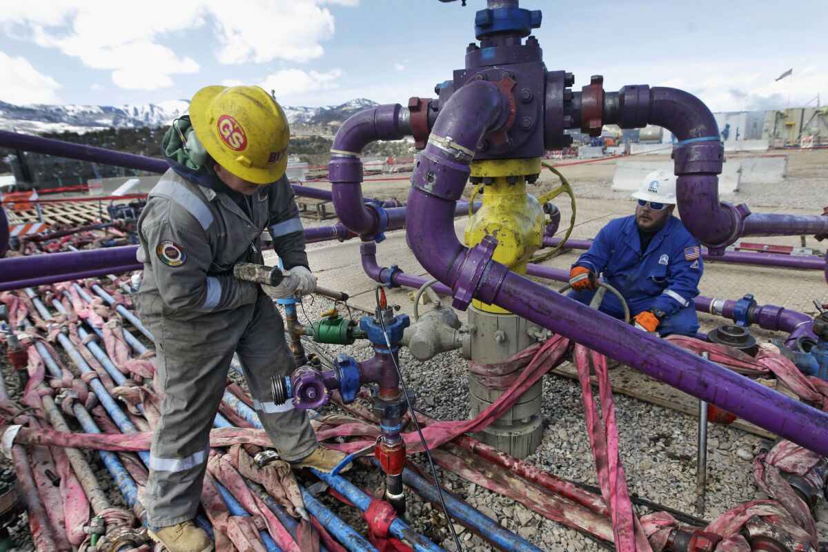 Workers tend to a wellhead during a hydraulic fracturing operation outside Rifle, in western Colorado, in 2013.
