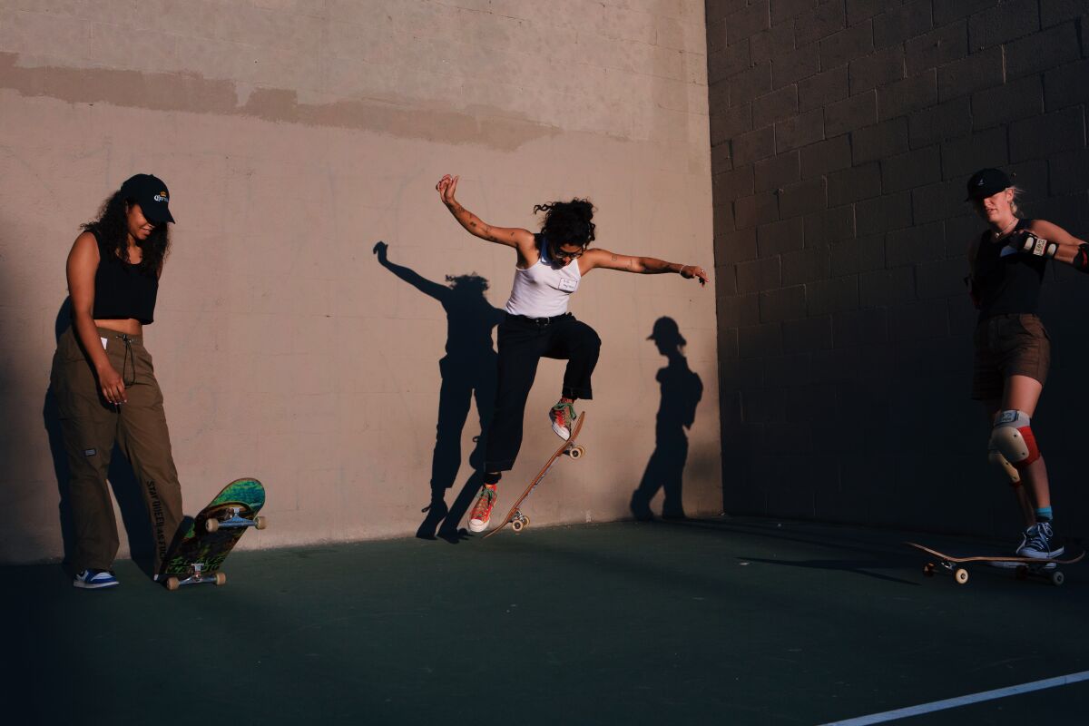 Three people practice skateboarding