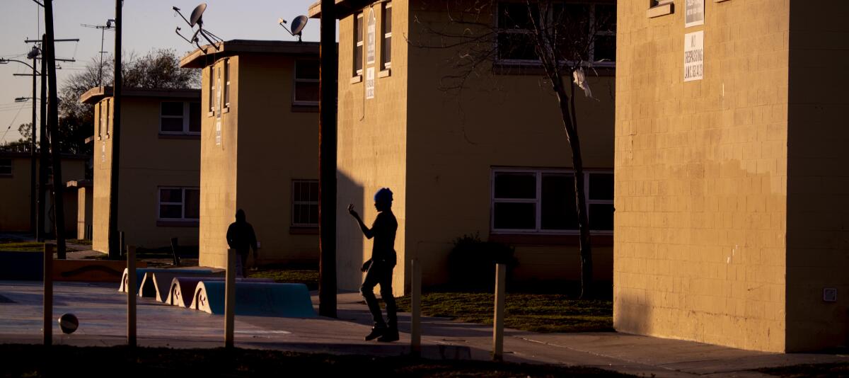A person is silhouetted walking near a series of four two-story buildings.