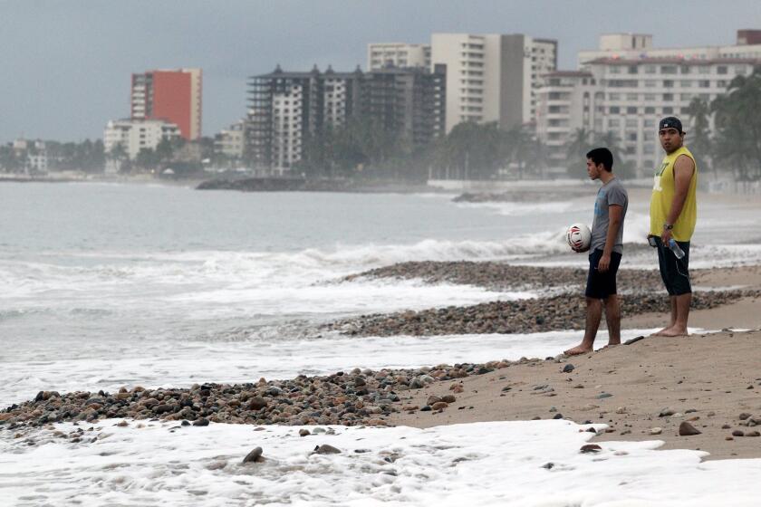 Two men visit a beach Saturday in Puerto Vallarta, Mexico, the day after Hurricane Patricia hit the country's West Coast. The resort town was unscathed by the powerful storm.