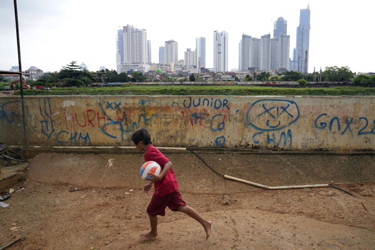 Boy holding a ball, with skyscrapers in the distance