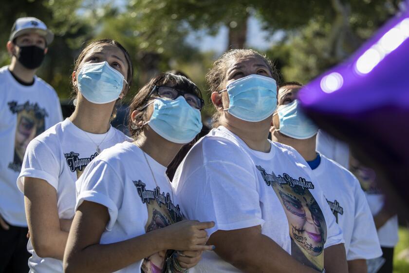 CATHEDRAL CITY, CA - DECEMBER 03: Family members Alexandria Cantu Macias, right, her daughter Gabriella Alvarado, center and Marianna Solares, left, watch balloons float away in honor of Tatyana Cantu Broughton, who died on November 2 from Covid-19, during a memorial service at Desert Memorial Park Thursday, Dec. 3, 2020 in Cathedral City, CA. (Brian van der Brug / Los Angeles Times)