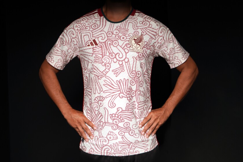An overall look at a white shirt with red outlined designs with arms akimbo.