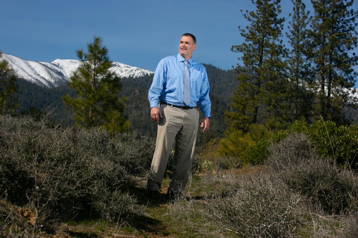 Jamie Green stands outside with snow-capped mountains in the background